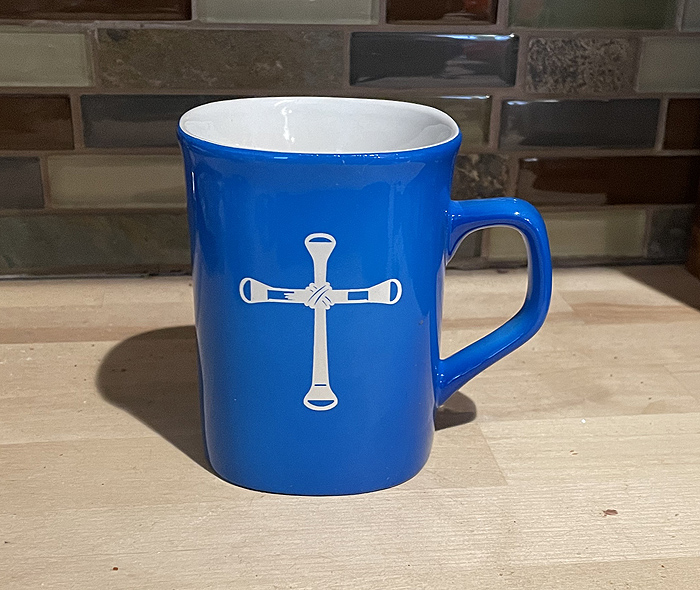 Blue ceramic round coffee mug with a horseshoe nail cross engraved on the front. Horse Mug