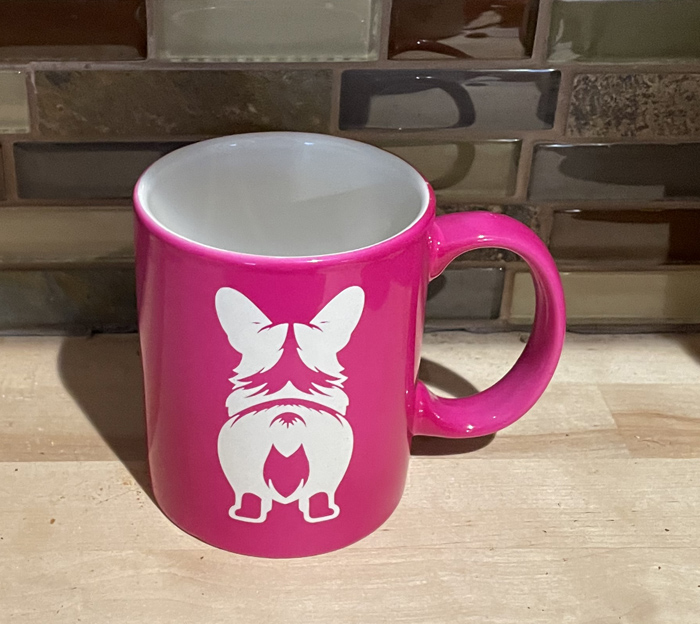 Pink ceramic round coffee mug with a corgi butt engraved on the front. Corgi Mug