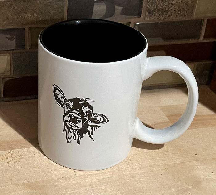 White ceramic round coffee mug with a cute cow head engraved on the front. Cow Mug