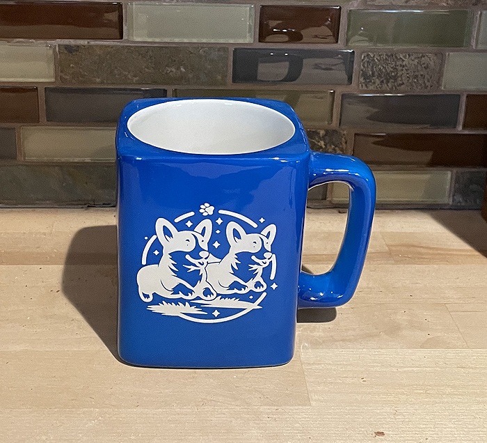 Corgis running square coffee mug that has 2 corgis running engraved on the front. Corgi Mug
