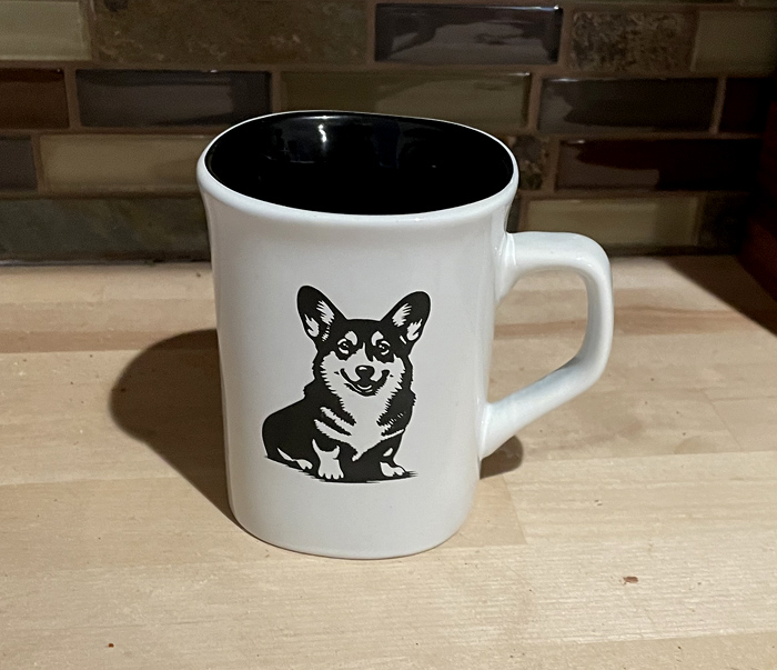 White ceramic round coffee mug with a sitting corgi engraved on the front. Corgi Mug