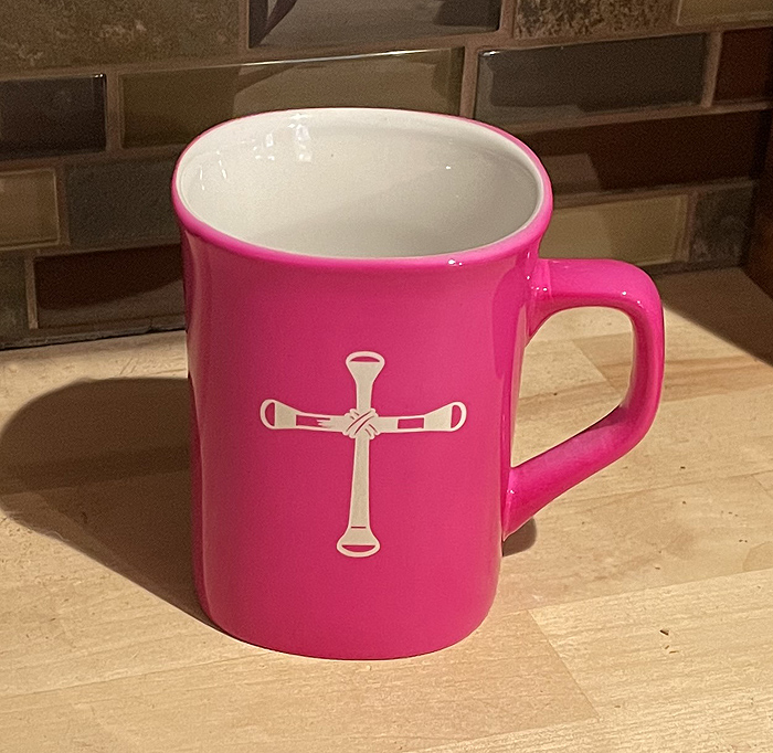 Pink ceramic round coffee mug with a horseshoe nail cross engraved on the front. Horse Mug